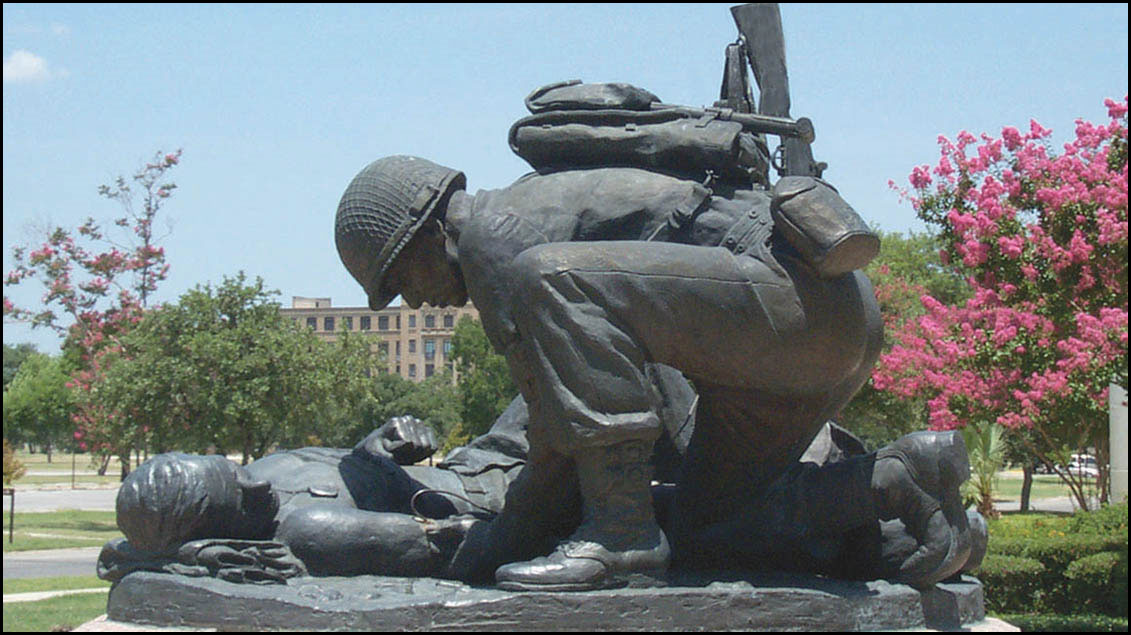 Statue of a soldier kneeling to help a wounded comrad